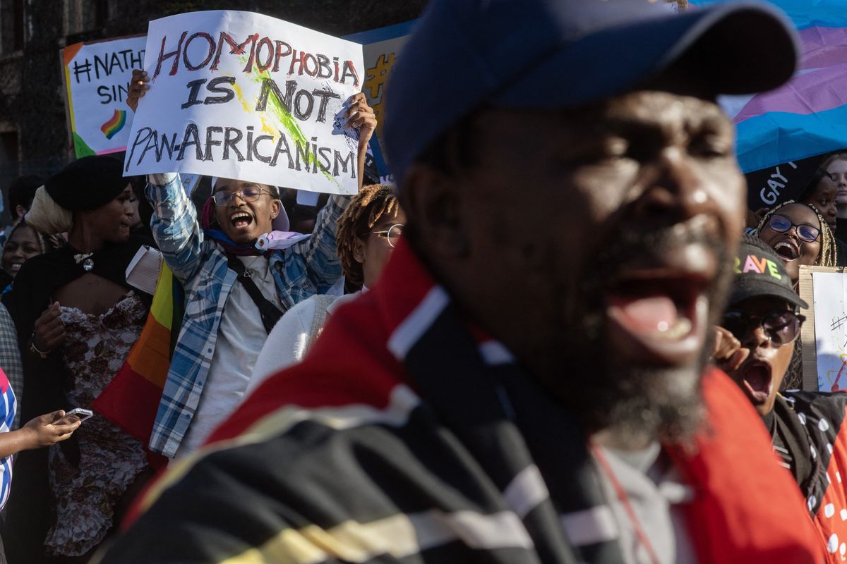 A photo of a pro-lgbtq protester with a placard that reads "Homophobia is not pan-Africanism."