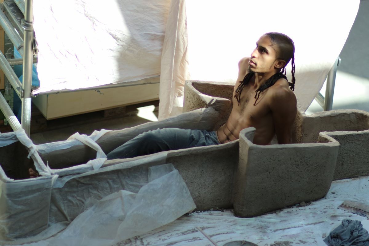 A photo of Ahmed Umar in a sarcophagus sculpture made in protest of queer oppression in his culture.