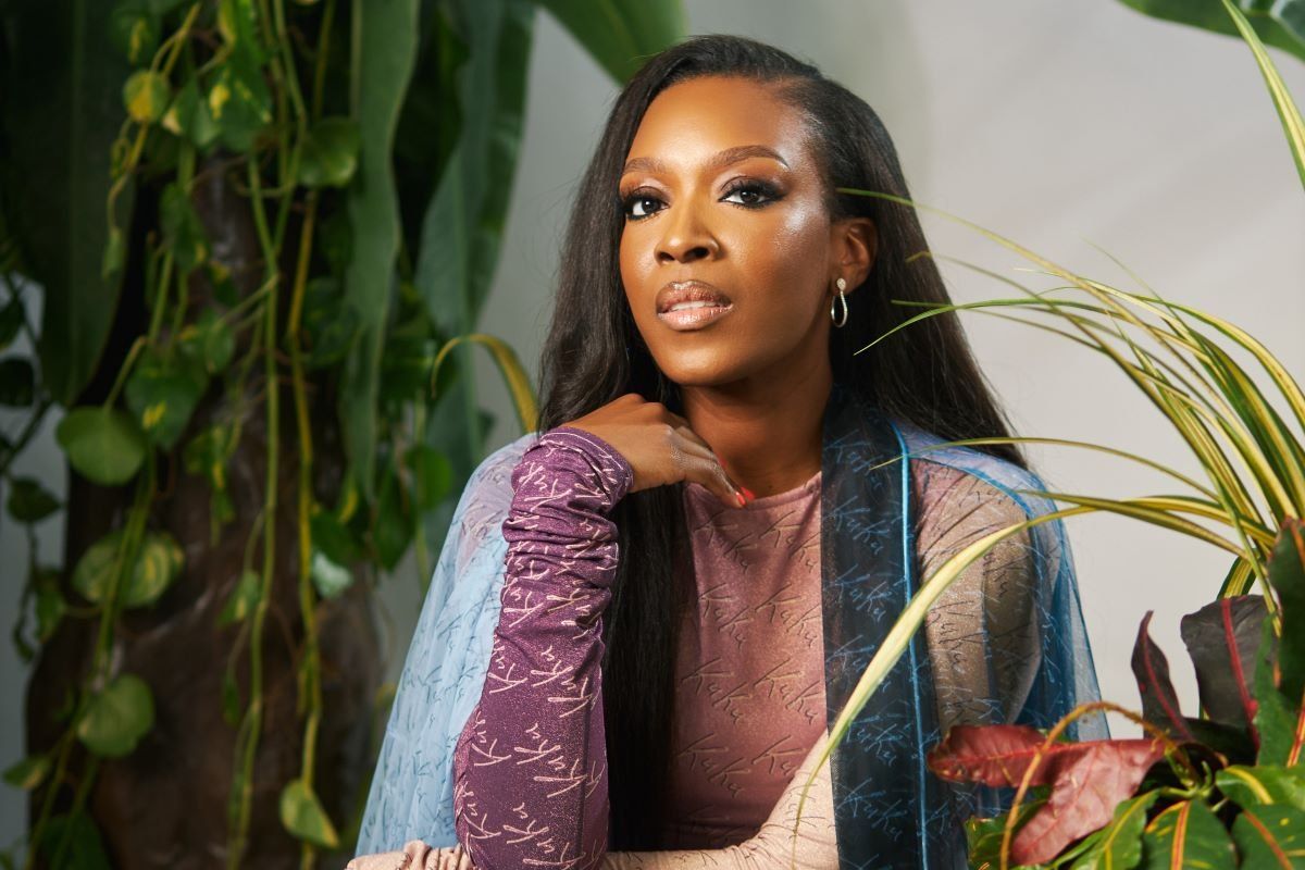 A photo of Banke Kuku sitting in a studio, surrounded by plants.