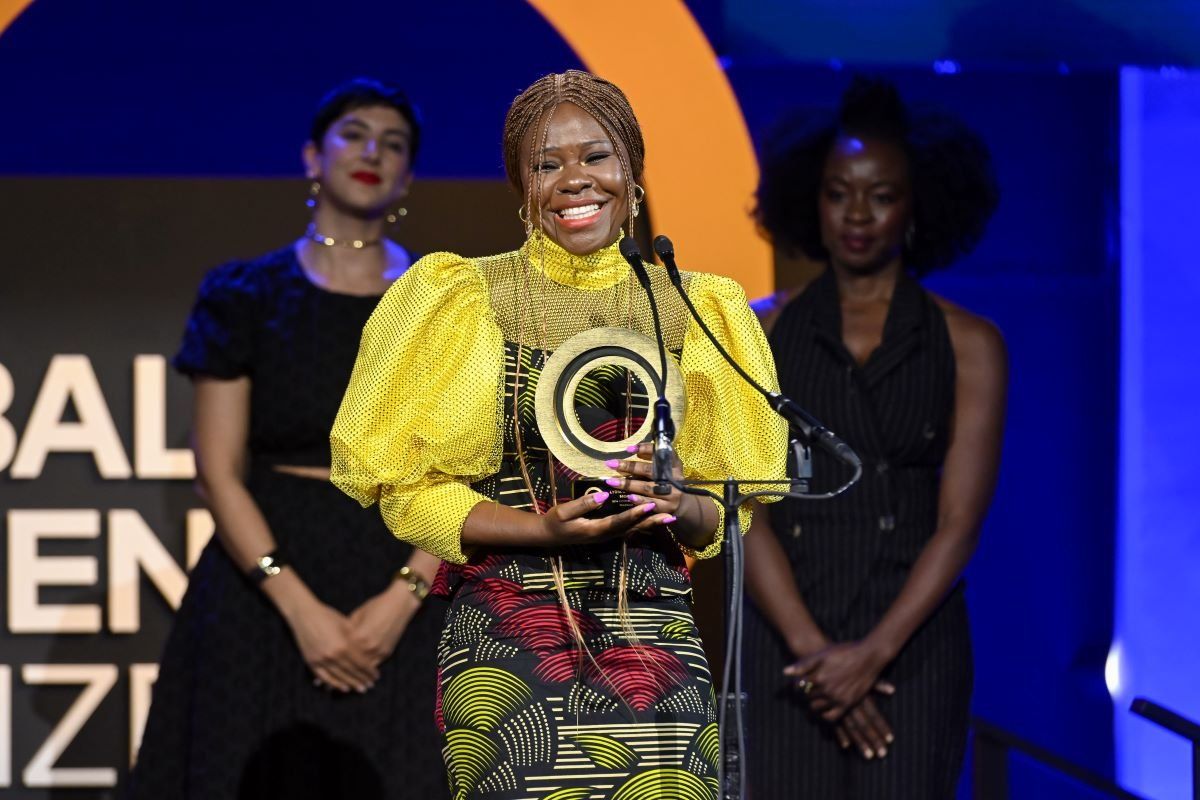 A photo of Citizen Award Recipient Lydia Charles Moyo speaking onstage (with Payzee Mahmod and Danai Gurira standing behind her) during the Global Citizen Prize event at Spring Studios on May 01, 2024 in New York City.