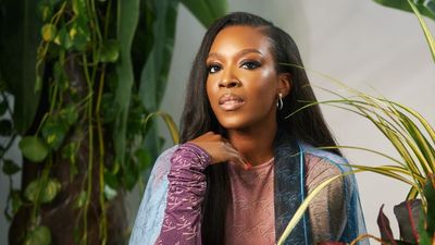 A photo of Banke Kuku sitting in a studio, surrounded by plants.