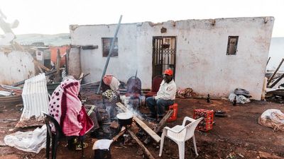Residents prepare breakfast outside their destroyed house in the aftermath of a tornado and extreme weather at an informal settlement in Tongaat, north of Durban on June 04, 2024. 