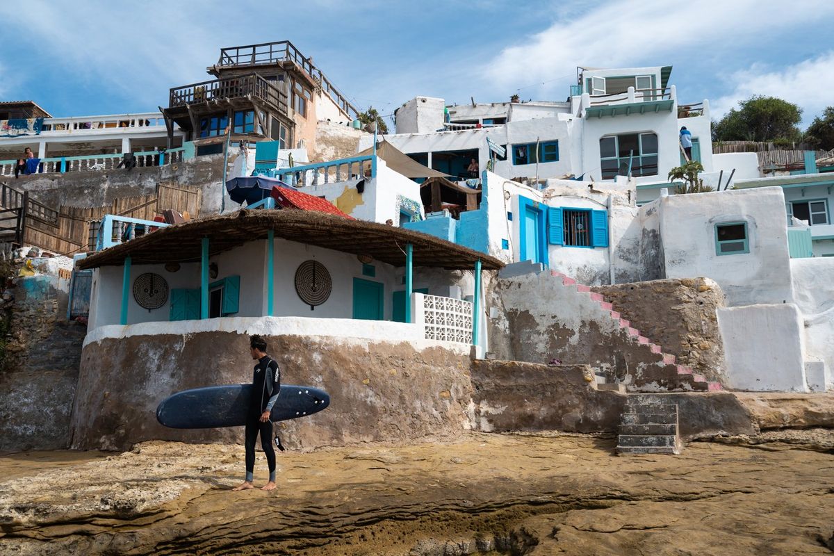 Surfer in "La Cathedrale" beach break surf spot with beach houses in the back.