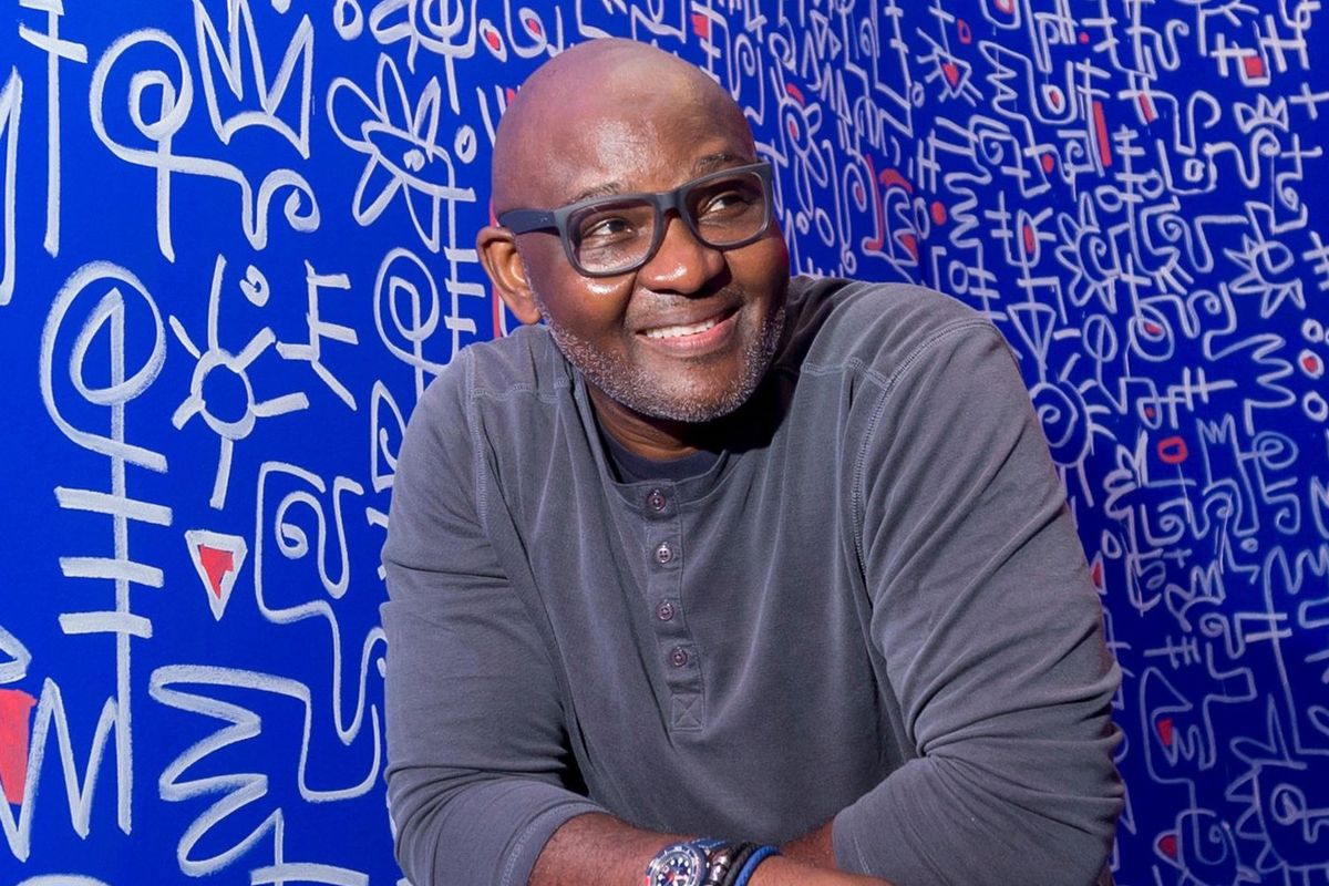 Victor Ekpuk against a backdrop of Nsibidi symbols.