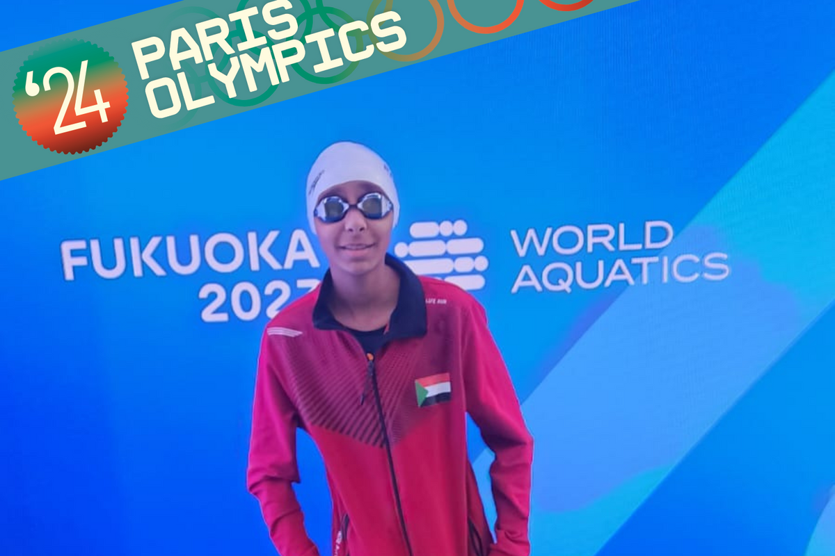 Rana Saadeldin standing in front of the blue World Aquatics Championships banner, wearing goggles.