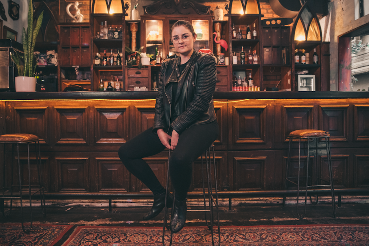 Woman wearing all black sitting on a bar stool.